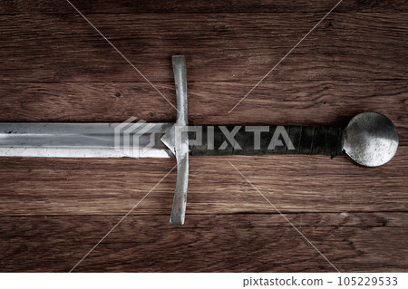 Medieval sword on wooden backgrond. Medieval sword on wooden backgrond. 105229533