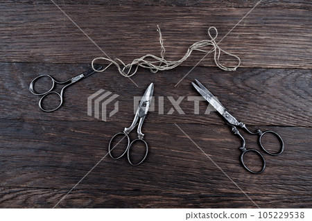 Antique old vintage retro scissors with thread on wooden table. Antique old vintage retro scissors with thread on wooden table. 105229538