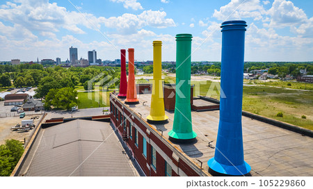 Close up of rainbow painted smokestacks at Science Central with distant downtown aerial 105229860