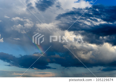 Amazing bright rainbow in a beautiful blue cloudy sky after rain and thunder Amazing bright rainbow in a beautiful blue cloudy sky after rain and thunder 105229874