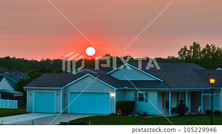 Lit lamppost dusk dawn sunrise sunset aerial single home focus in neighborhood forest tree skyline Lit lamppost dusk dawn sunrise sunset aerial single home focus in neighborhood forest tree skyline 105229946