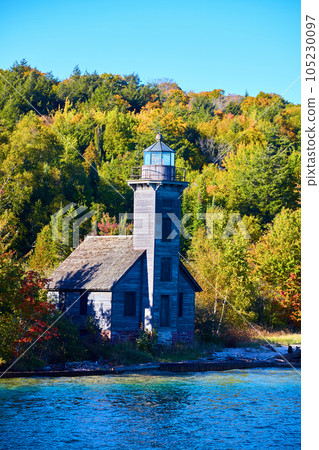 Lighthouse on Lake Superior shore with boarded up windows and green forest beyond Lighthouse on Lake Superior shore with boarded up windows and green forest beyond 105230097