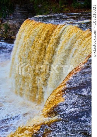 Large Tahquamenon Falls waterfall with murky brown-orange waters and blue river with distant cliff Large Tahquamenon Falls waterfall with murky brown-orange waters and blue river with distant cliff 105230323