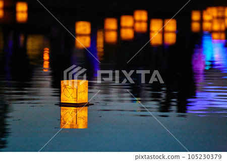 Lone lantern on dark pond with neon lights and distant lanterns in background 105230379