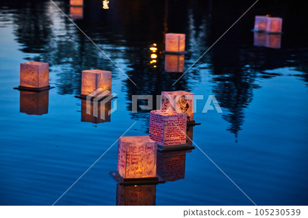 Nine lanterns floating on water with trees reflected on waters surface Nine lanterns floating on water with trees reflected on waters surface 105230539