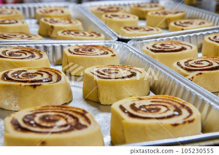 Fresh pre-baked cinnamon rolls in silver trays Fresh pre-baked cinnamon rolls in silver trays 105230555