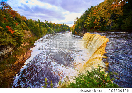 Tahquamenon Falls waterfall with large basin, white flowing river rapids, and green fall forest Tahquamenon Falls waterfall with large basin, white flowing river rapids, and green fall forest 105230556