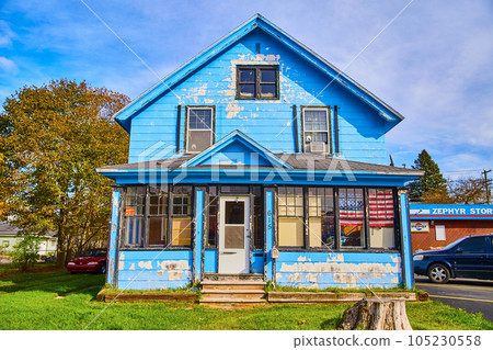 Blue house with chipped blue paint American flag, tree stump, red car, and old home Blue house with chipped blue paint American flag, tree stump, red car, and old home 105230558
