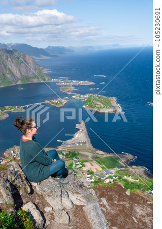 Alone happy woman hiker enjoys the view on cliff edge of lofoten islands, in Norway, Reinebringen 105230691