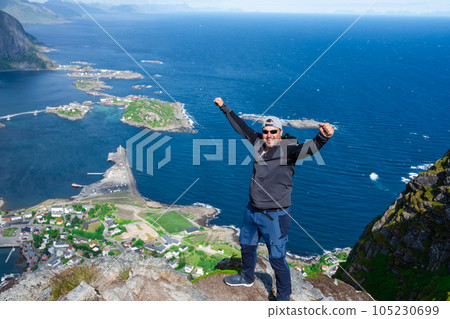 Relaxed happy hiker enjoys stunning views on Reinebringen peaks of Lofoten islands, fjords, Norway Relaxed happy hiker enjoys stunning views on Reinebringen peaks of Lofoten islands, fjords, Norway 105230699