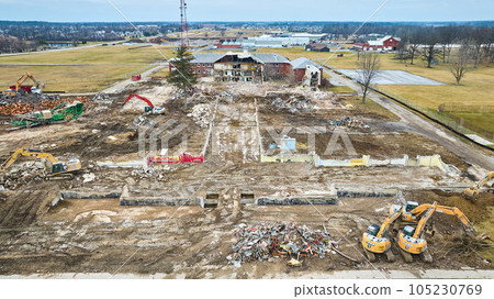 Aerial of construction vehicles near a destroyed building with debris 105230769
