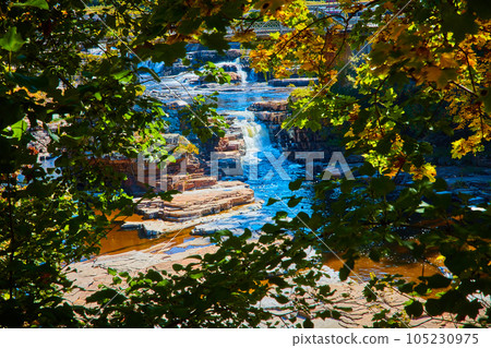 View through trees of cascading waterfalls over cliffs View through trees of cascading waterfalls over cliffs 105230975