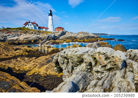 White lighthouse overlooking rocky coast in Maine with focus on rocks like petrified wood White lighthouse overlooking rocky coast in Maine with focus on rocks like petrified wood 105230980