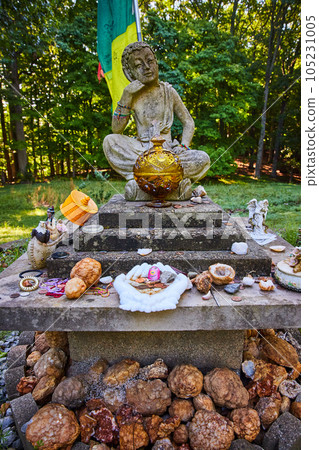 Geodes donated to small stone Tibetan Mongolian Buddhist statue in forest 105231005