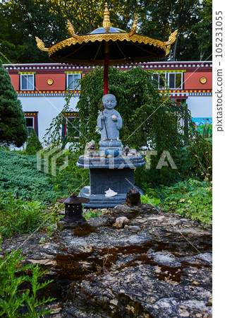 Religious statue in garden with golden umbrella 105231055