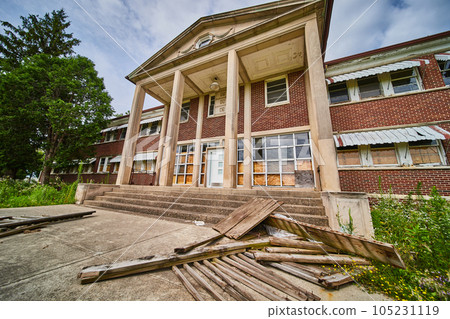 Stunning stone and brick entrance of abandoned building with broken wood and overgrown fields 105231119