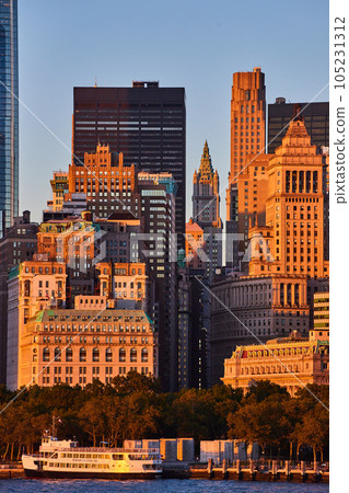 Empire State Building through streets of New York City from off of coast in golden glow sunset dusk light Empire State Building through streets of New York City from off of coast in golden glow sunset dusk light 105231312