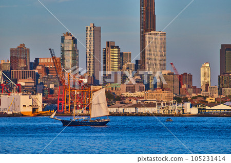 Skyline of New York City behind ship sailing in bay during golden hour Skyline of New York City behind ship sailing in bay during golden hour 105231414