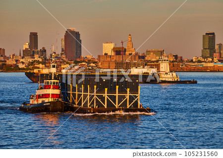 Golden hour New York City bay with merchant ship pulling shipping containers Golden hour New York City bay with merchant ship pulling shipping containers 105231560