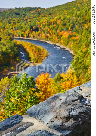 Forest in early fall with river winding through and damaged wall in focus of foreground 105231630