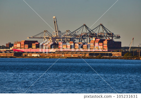 Large ship full of shipping containers loading on coast of New York City in golden hour light Large ship full of shipping containers loading on coast of New York City in golden hour light 105231631
