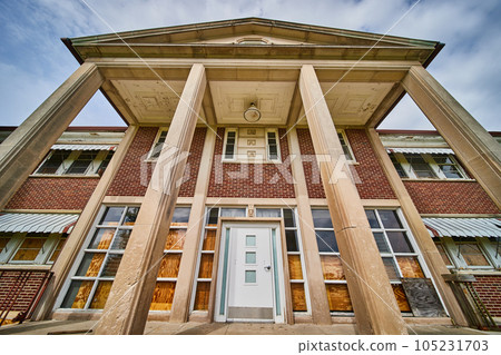 Huge stone pillars at entrance to abandoned hospital building in America 105231703