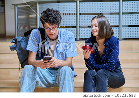 Friends college students guy and girl with smartphones inside educational building 105233688