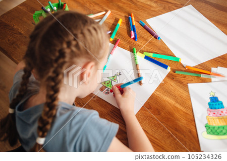 The child spends time creating and drawing. A girl draws a Christmas tree with felt-tip pens. High quality photo The child spends time creating and drawing. A girl draws a Christmas tree with felt-tip pens. High quality photo 105234326