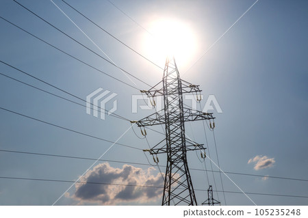 High voltage tower with power wires against the background of the sun and cloud High voltage tower with power wires against the background of the sun and cloud 105235248