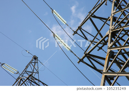 High voltage tower with power wires against the background of the sun and cloud 105235249