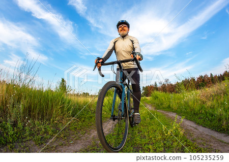 bearded man cyclist rides a bike on a road in nature. sports, hobbies and entertainment for health bearded man cyclist rides a bike on a road in nature. sports, hobbies and entertainment for health 105235259