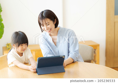 Parent and child looking at a tablet in the living room Parent and child looking at a tablet in the living room 105236533