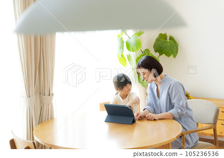 Parent and child looking at a tablet in the living room 105236536