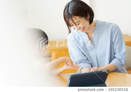 Parent and child looking at a tablet in the living room 105236538