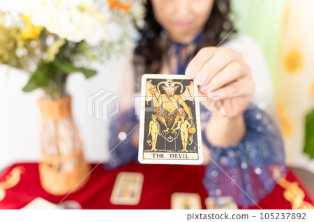 A fortune teller holding out a tarot card (THE DEVIL) 105237892