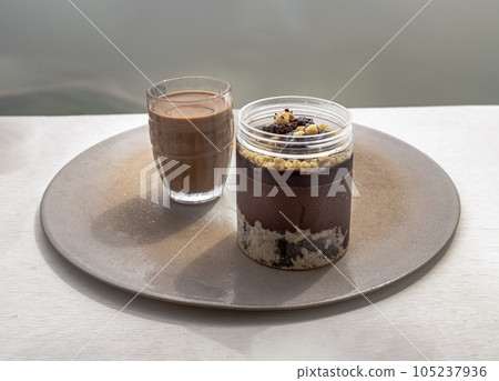 Good morning with Crumble dark chocolate brownie served with Coffee in glass cup on Ceramic tray. Good morning with Crumble dark chocolate brownie served with Coffee in glass cup on Ceramic tray. 105237936