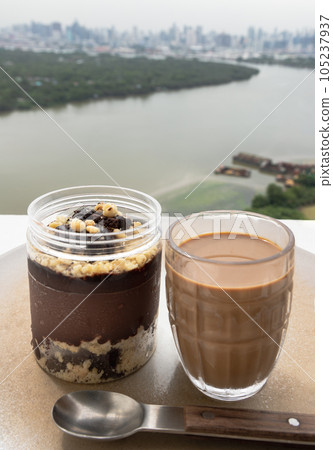 Good morning with Crumble dark chocolate brownie served and Coffee in glass cup served with spoon with river view. Good morning with Crumble dark chocolate brownie served and Coffee in glass cup served with spoon with river view. 105237937