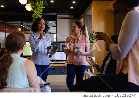 Diverse female colleagues in discussion using tablet in casual office meeting Diverse female colleagues in discussion using tablet in casual office meeting 105239277