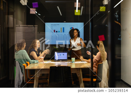 Diverse casual businesswomen in discussion using tablet and laptop in meeting room 105239314