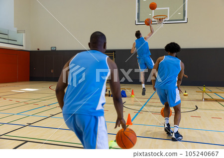 Diverse male basketball players exercising and playing basketball at gym Diverse male basketball players exercising and playing basketball at gym 105240667