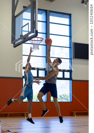 Caucasian male basketball players wearing blue sports clothes and playing basketball at gym 105240684