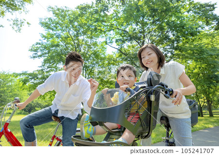Parents riding a bicycle in a fresh green park Parents riding a bicycle in a fresh green park 105241707