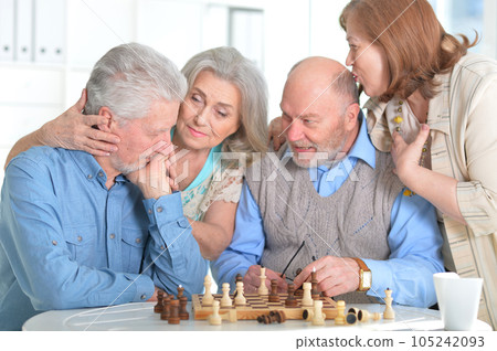 Four elderly people play a game of chess together  105242093