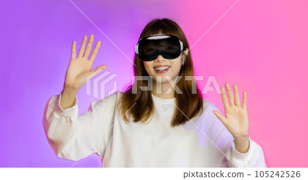 Asian woman wearing AR glasses vision pro and pointing finger isolated on pink and purple neon background 105242526