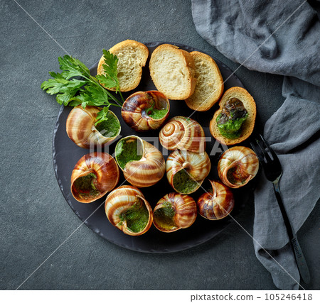 plate of baked escargot snails filled with parsley and garlic butter plate of baked escargot snails filled with parsley and garlic butter 105246418
