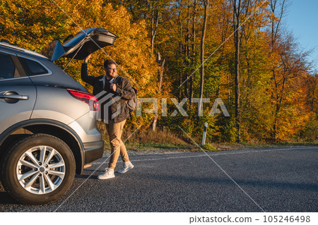 a smiling man with a backpack on his back closes the trunk of the car. copy space a smiling man with a backpack on his back closes the trunk of the car. copy space 105246498