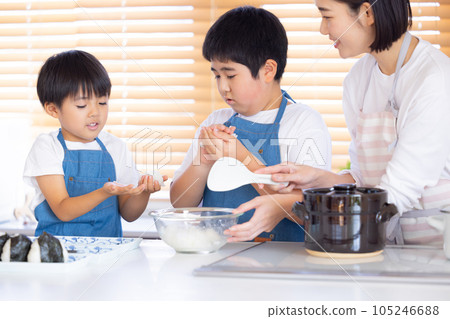 A boy making rice balls with freshly cooked rice 105246688