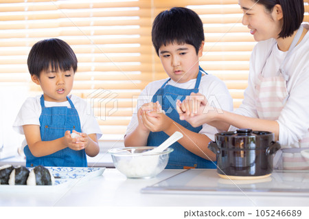A boy making rice balls with freshly cooked rice 105246689