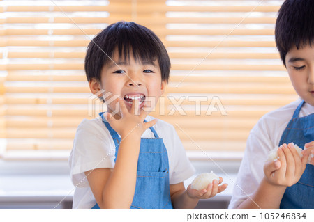A boy making rice balls with freshly cooked rice A boy making rice balls with freshly cooked rice 105246834