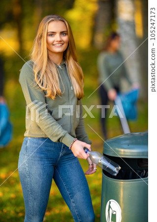 Beautiful smiling young woman putting bottle in garbage bin 105247173
